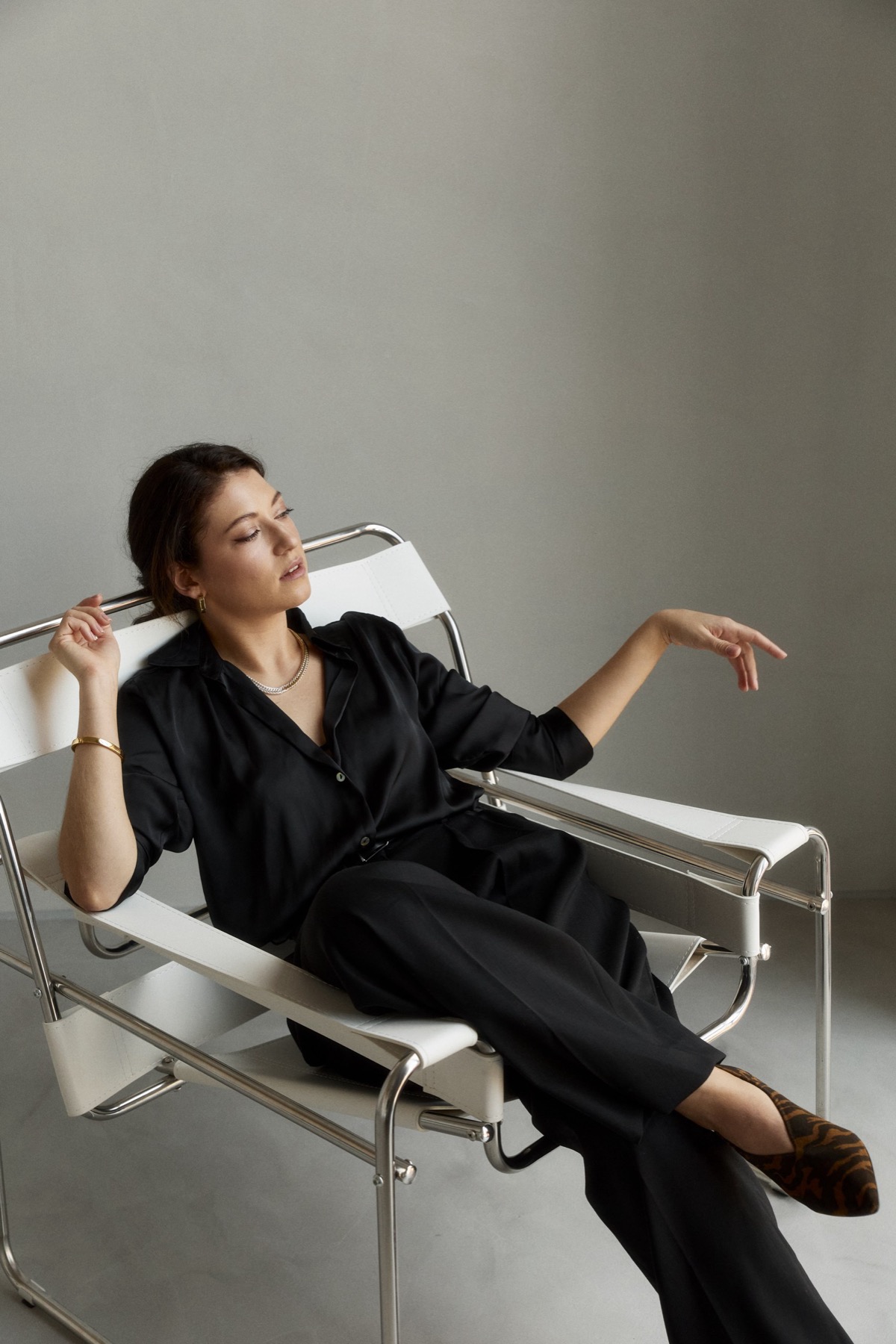 Ksenia in black, seated in a chrome and white chair